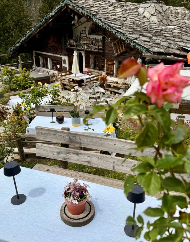 Une vue captivante de l'intérieur ou de la terrasse de l'Alpine Garden Restaurant, mettant en scène son cadre idyllique face aux majestueux sommets de Chamonix. L'image sublime l'atmosphère unique du lieu, où la haute gastronomie et la beauté naturelle s'entremêlent pour offrir une expérience culinaire d'exception.